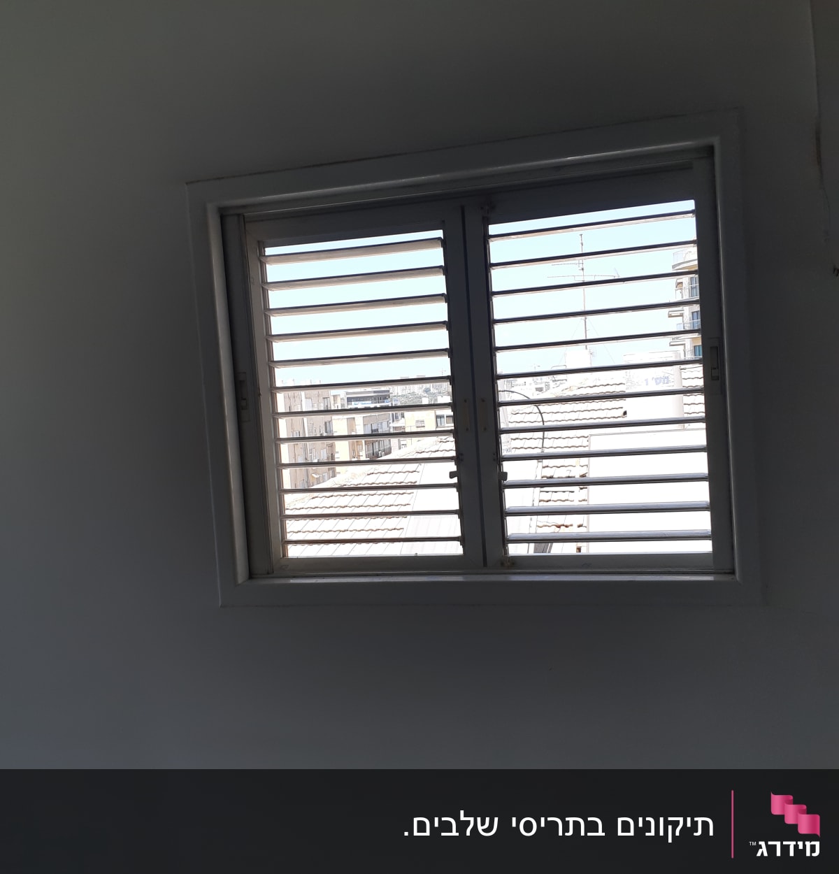 תריסים לבנים פתוחים בחלון על קיר לבן